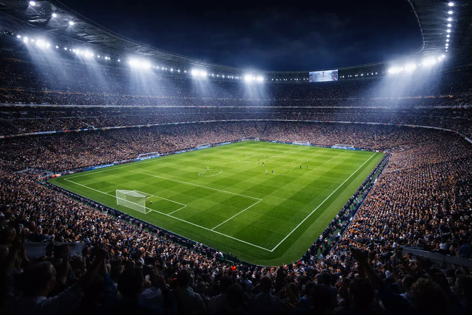 Estadio de fútbol lleno de aficionados bajo las luces nocturnas